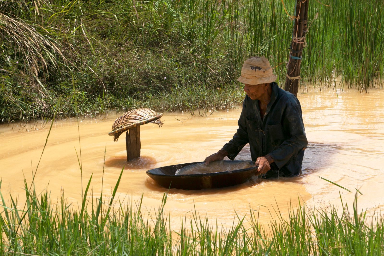 Artisanal miner panning for gold in a waterway